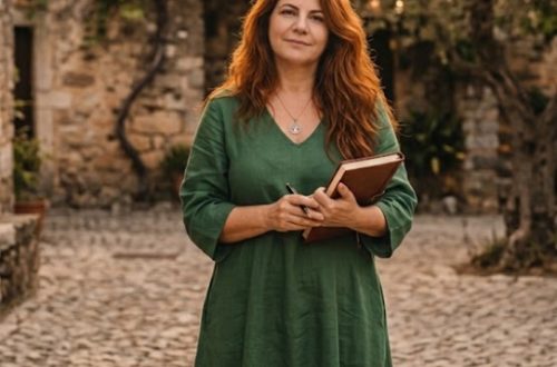 Dan Dronacharya escritora do livro Entre Mundos e Almas descalça segurando um caderno e caneta